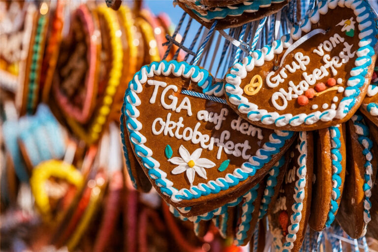 Ein Foto von Lebkuchenherzen, die auf dem Oktoberfest an einem Stand hängen. Das Lebkuchenherz im Vordergrund trägt die Aufschrift: TGA auf dem Oktoberfest. Die Lebkuchenherzen sind typisch für das Oktoberfest dekoriert.